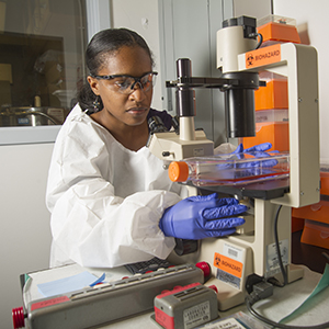 "female scientist testing something under a microscope"