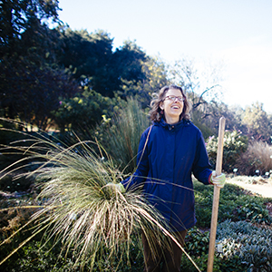 "woman outdoors holding a plant and smiling"