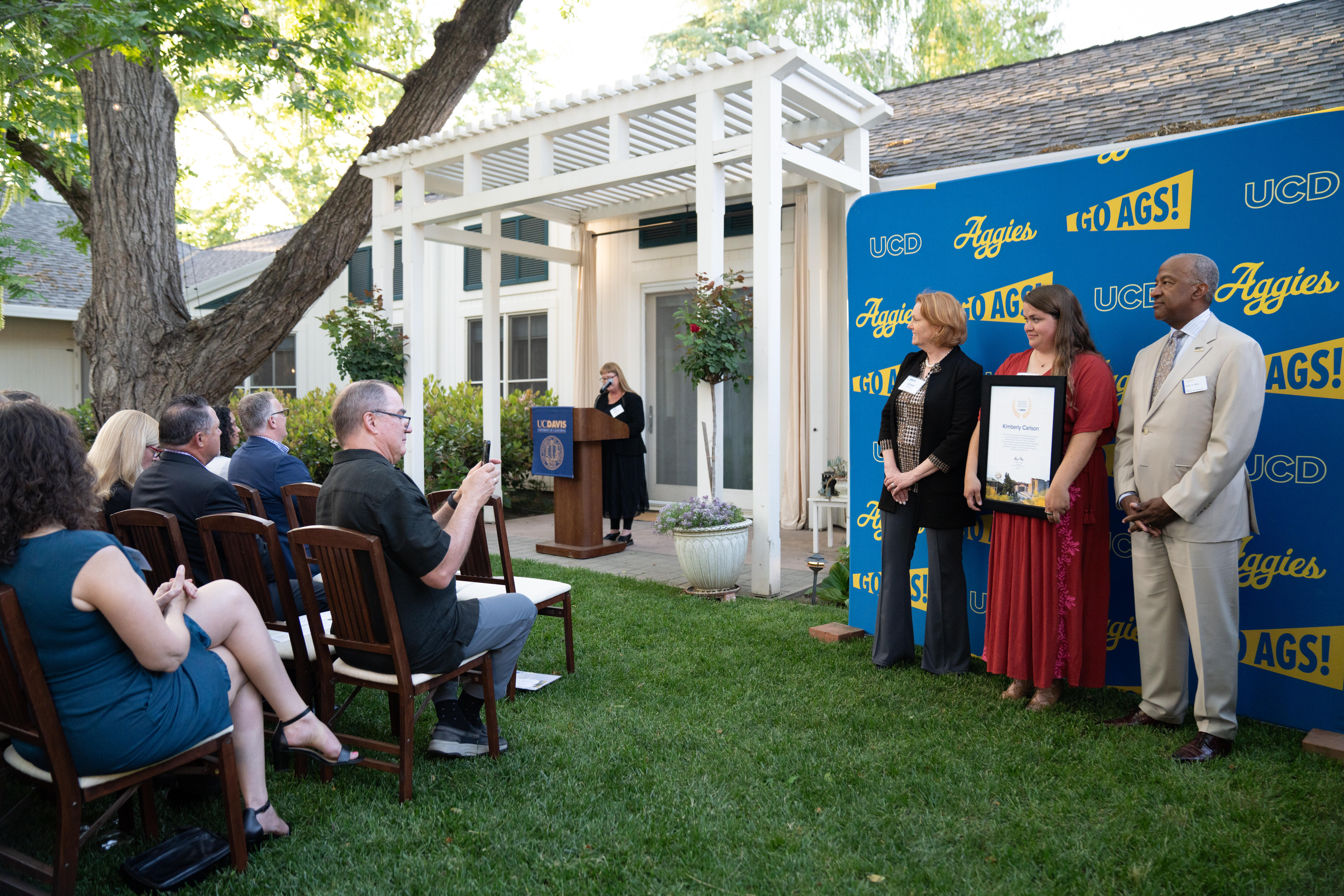 An award recipient standing and posing with Clare Shinnerl and Gary May.