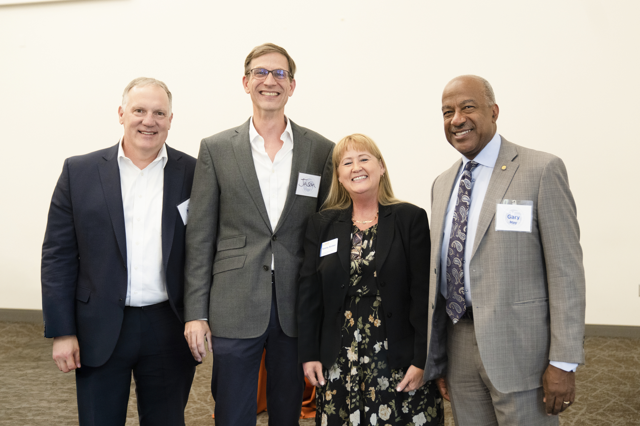 Four professionals wearing name badges, smiling together in a conference room
