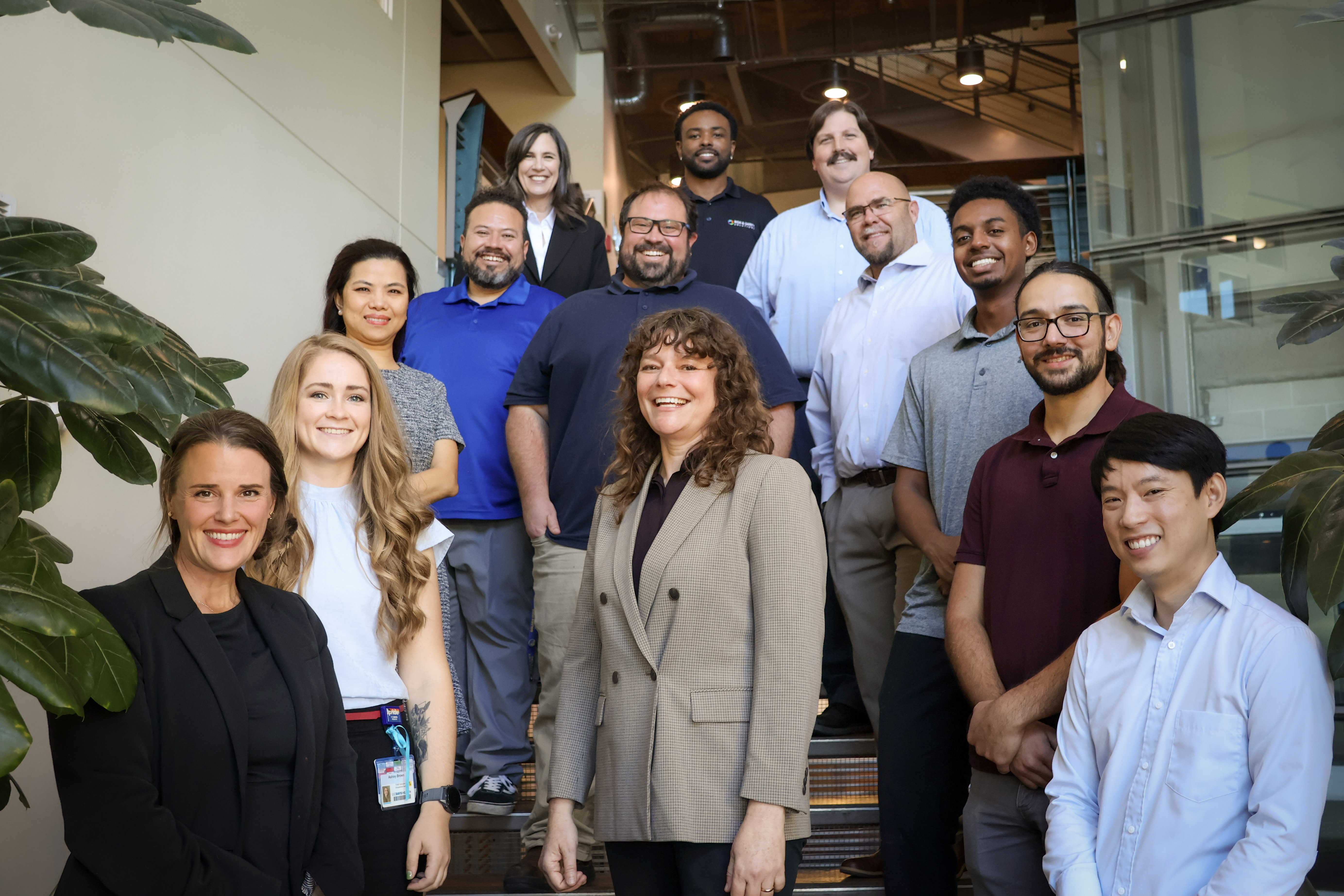Diverse office team in casual business attire smiling on indoor staircase