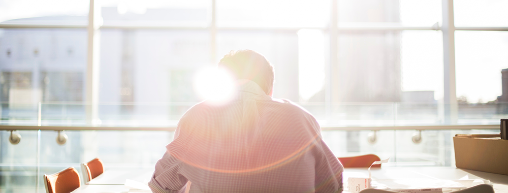 man at his computer with a ray of sun over his shoulder