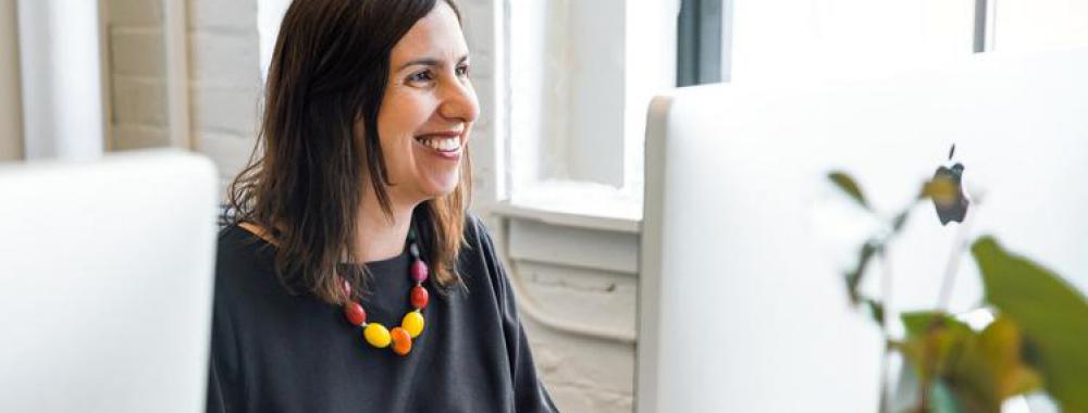 woman smiling and using her computer