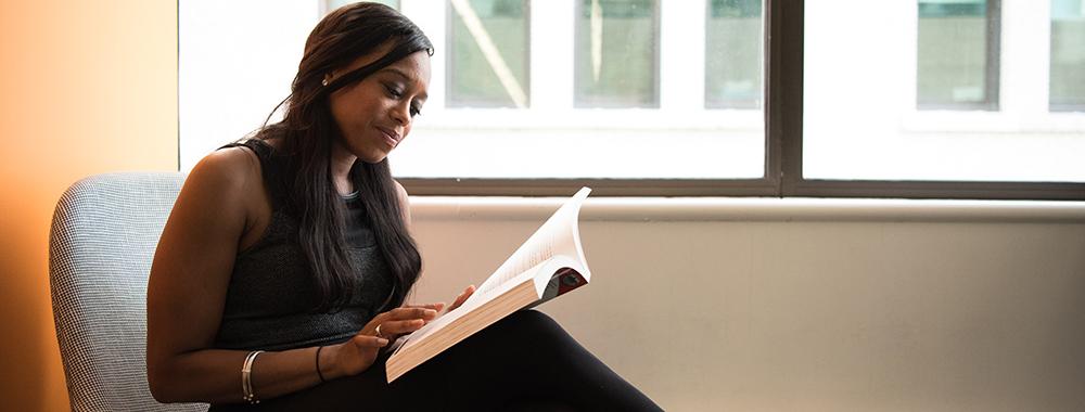 woman sitting by a window reading a book