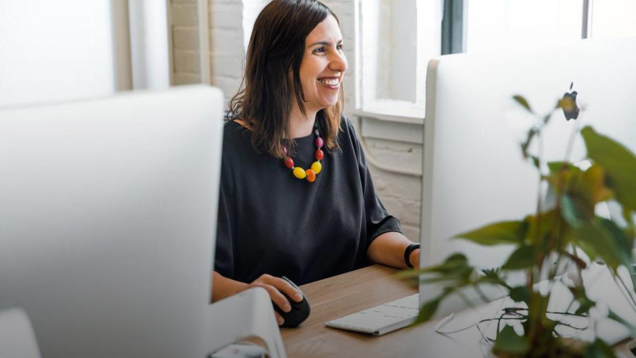 women smiling while sitting behind her computer working