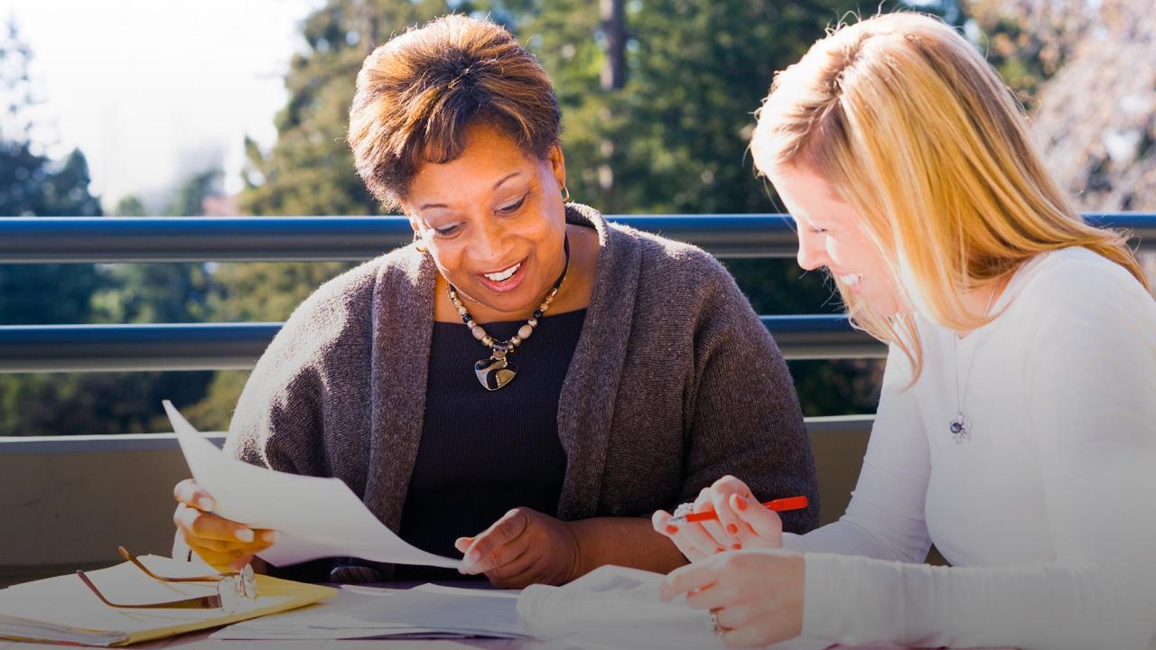Photo of two people reviewing documents together.