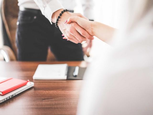 man and woman shaking hands over a desk