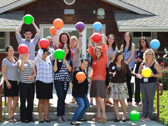 group of smiling people holding colorful balloons