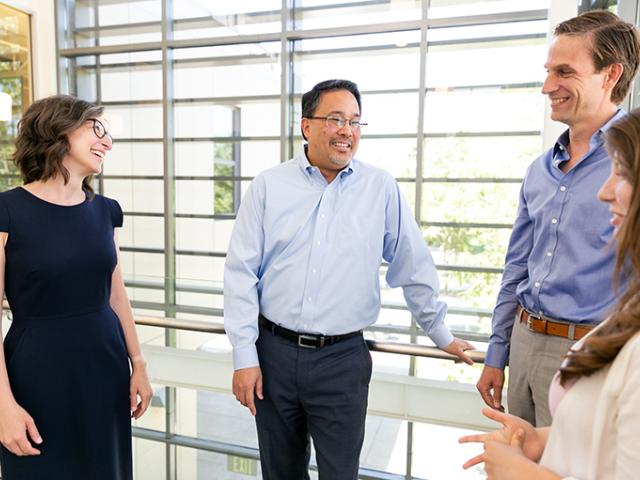 man talking to a group of colleagues and smiling