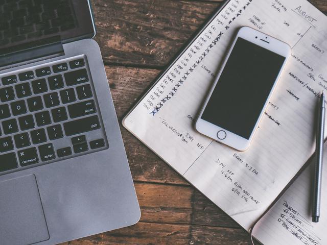 laptop alongside cell phone and notebook