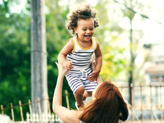 small boy being thrown into the air by his mother