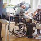 Person in wheelchair at a desk talking to someone else.