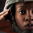 female soldier saluting in front of an american flag