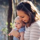 young mother smiling and holding her newborn child