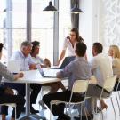 young woman talking to a group around a conference table