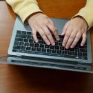 Persons hands typing on laptop.