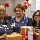 Three women celebrating at a table, surrounded by heart balloons.