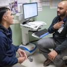 Doctor and patient are speaking sitting across from one another.  