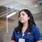 Nurse is sitting, looking off into the distance.  She looks as if she is contemplating something.  