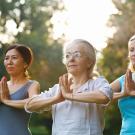 Three women are doing a yoga pose outdoors.  