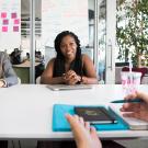 two female colleagues listening to another coworker across a conference table