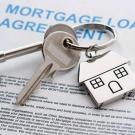 stock image of keys with a house charm atop a mortgage loan agreement