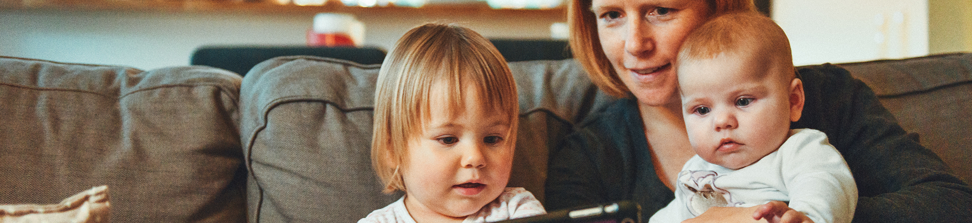 mother reading on an ipad with her two young children