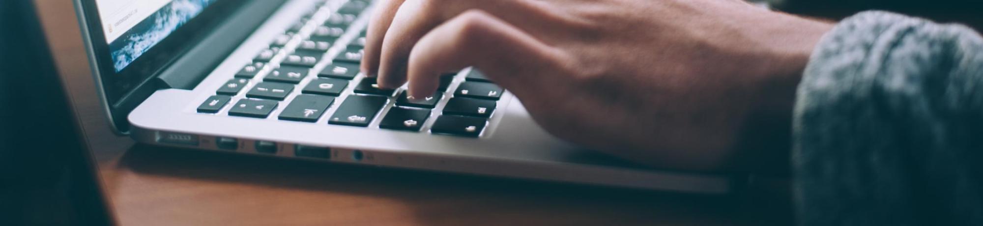 Person typing on a laptop computer.